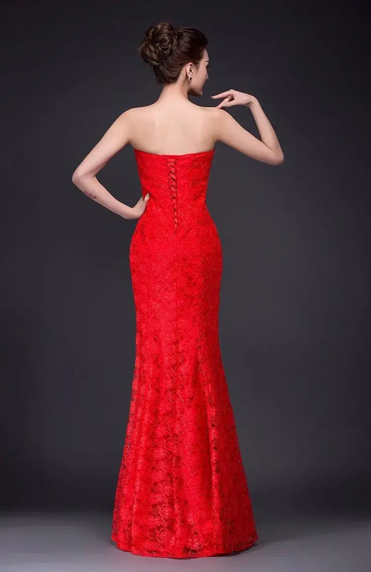 A vibrant red strapless lace mermaid wedding dress with a fitted bodice, central back zipper, and flowing long dress fuchsia skirt shown from the back side.