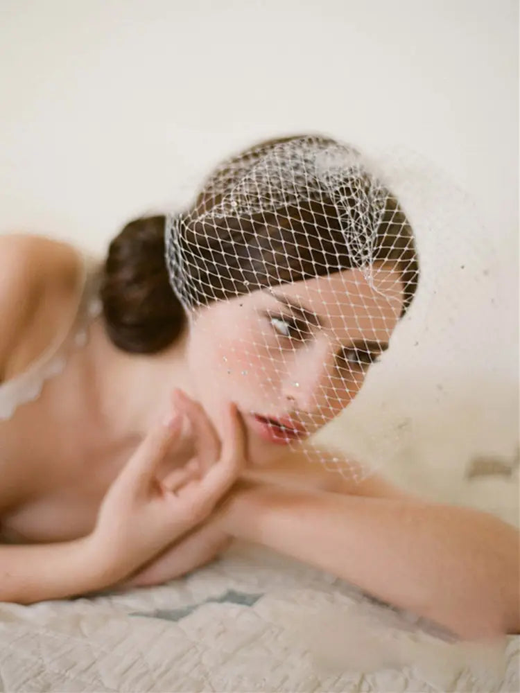 a delicate white mesh bridal veil rhinestone large hole mesh headdress with subtle sheen elegantly draped over the model’s head