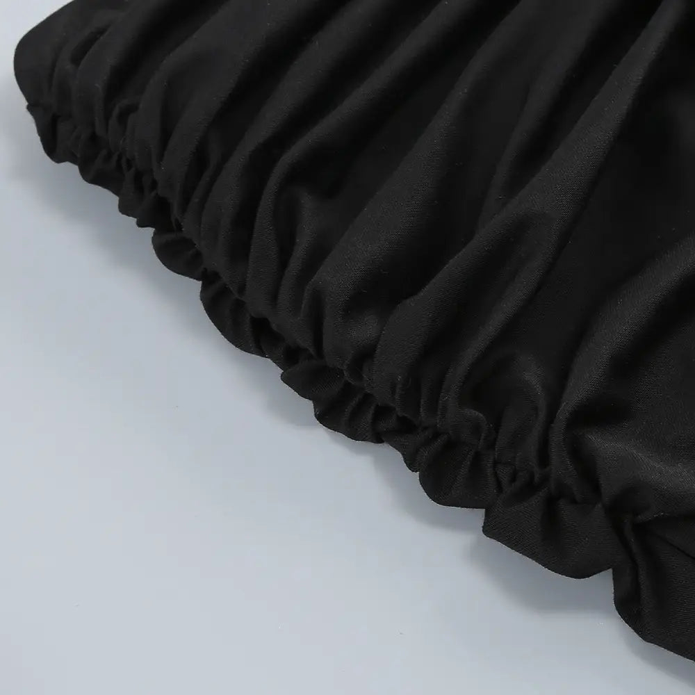 Black ruffled fabric with a soft flowing texture on a black V-neck backless long sleeves skirt waist gown.