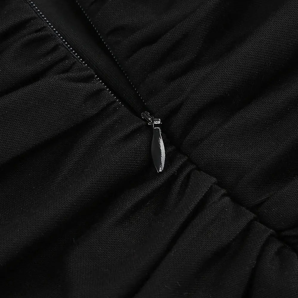black zipper pull with sleek metallic finish on textured black fabric of backless long sleeves skirt waist gown.