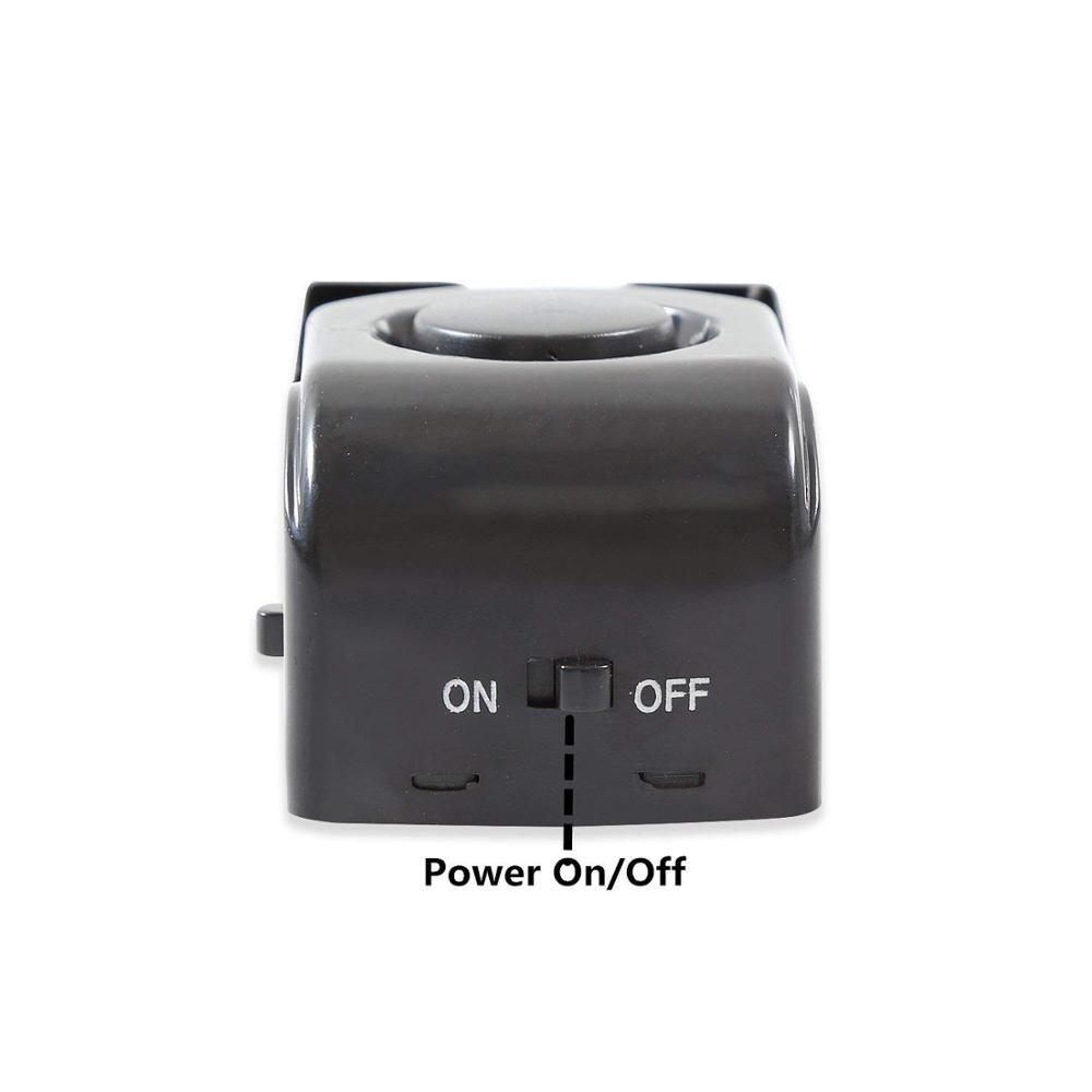 Black plastic electronic burglar alarm wedge door stop with a circular button on top and a power on/off switch for intelligent security.