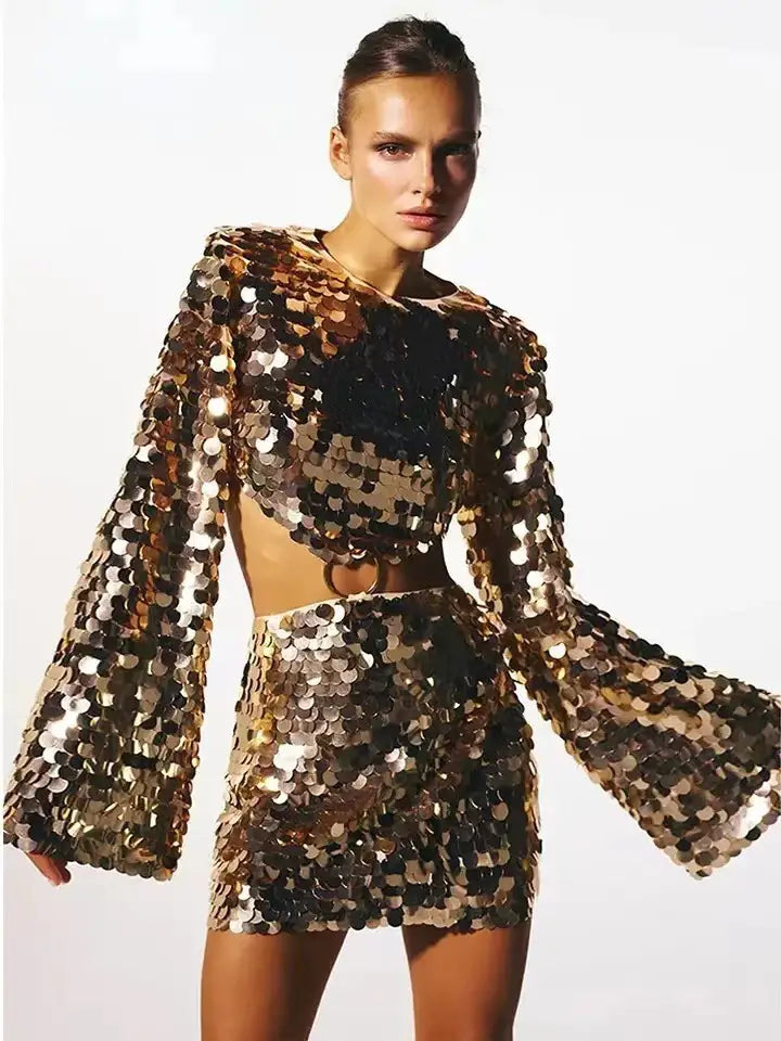 a shimmering gold and black sequined evening dress with long sleeve round neck and flared sleeves in a two-piece design