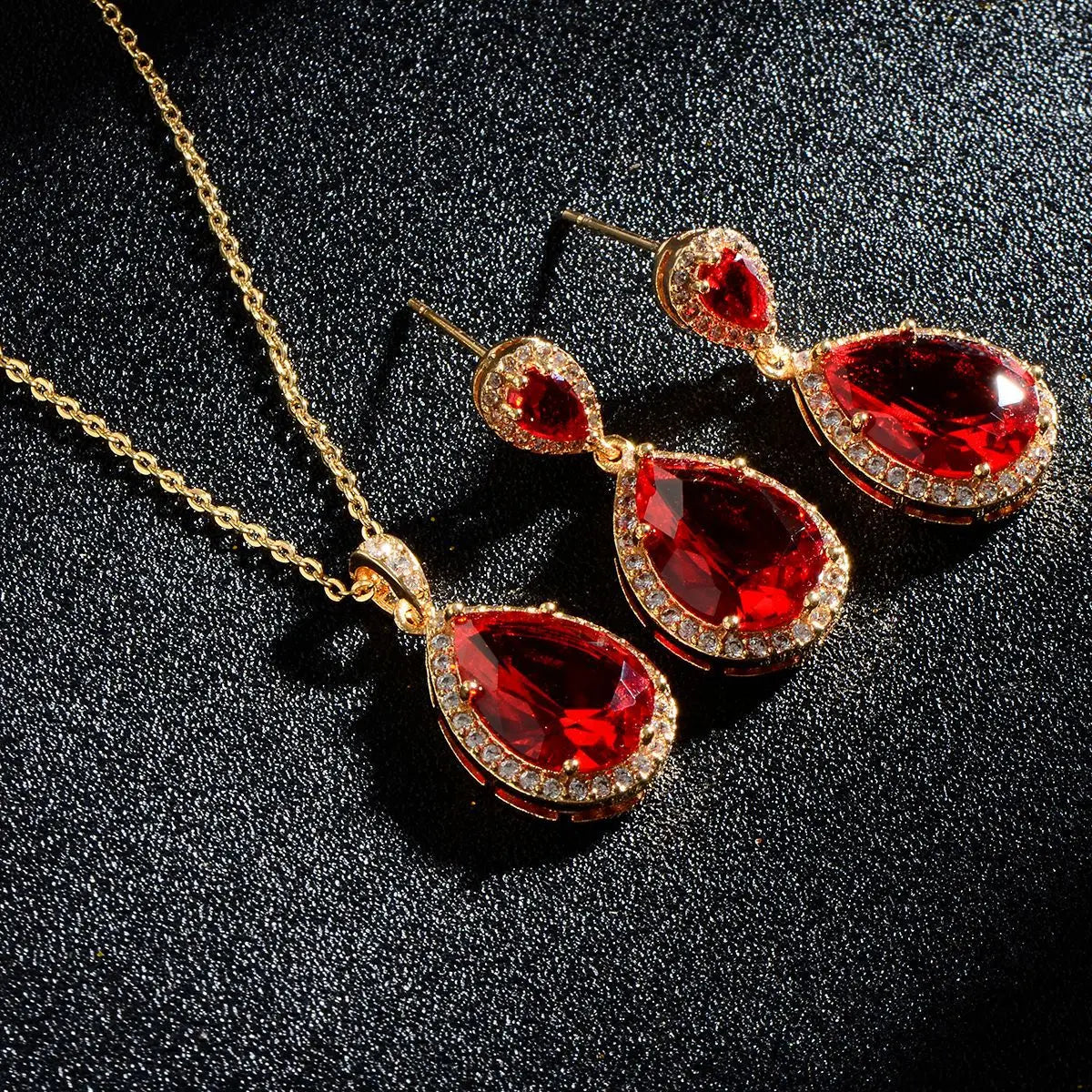 Elegant gold-toned jewelry set with teardrop-shaped red bright big zircon gemstones accented by sparkling clear zircon water drops.