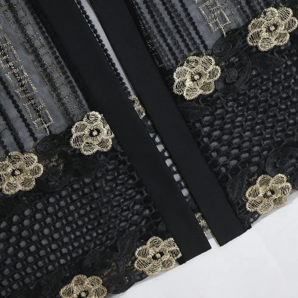 black lace fabric with intricate gold floral embroidery on the teal gold embroidered vest dress kraft abaya showcasing elegant detailing on the dress kraft tan design