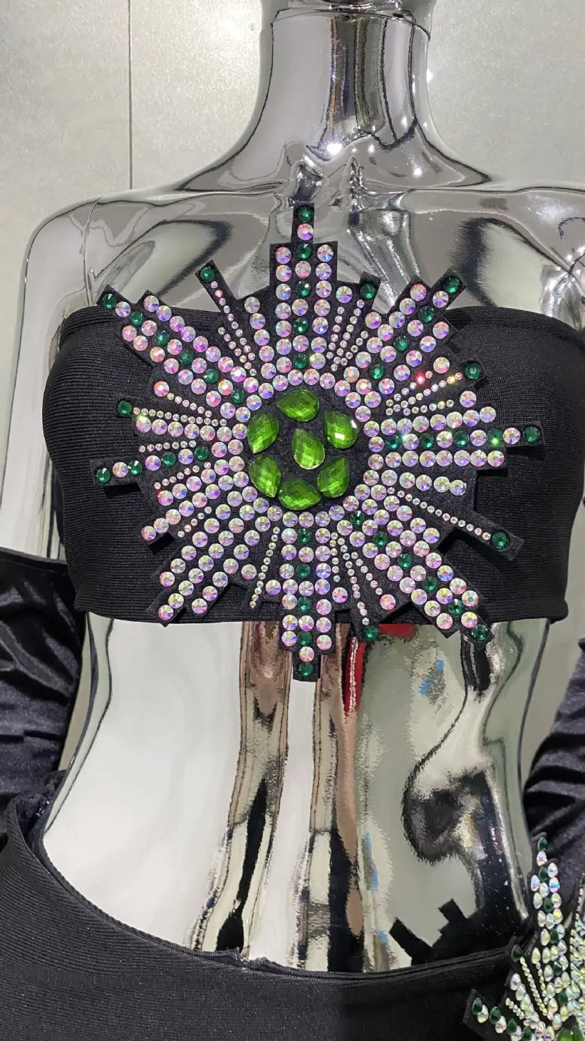 black strapless top with a radiant starburst design of green and iridescent rhinestones paired with a shiny rhinestone tube high slit skirt bandage suit