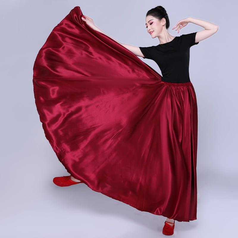 A flowing deep red satin solid color performance skirt with a smooth glossy finish and a high waisted design.
