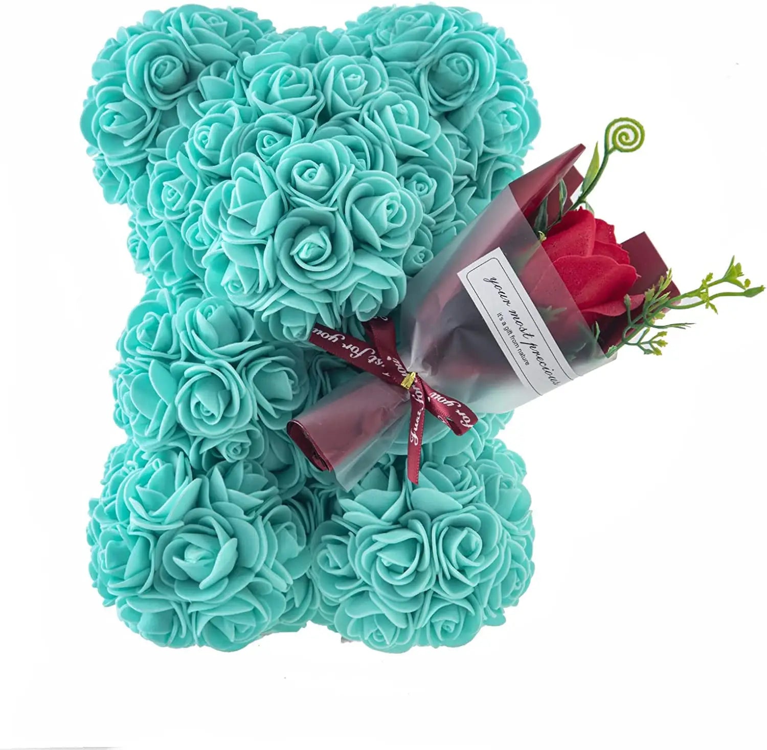 A turquoise rose bear figurine covered in roses holding a small bouquet of red roses wrapped in clear cellophane with a maroon ribbon featured in a red rose bear eternal flower gift box.