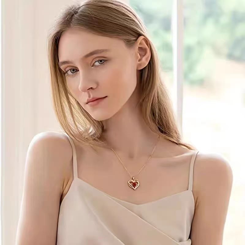 Gold heart pendant necklace featuring a red sapphire pendant center in a polished gold setting.