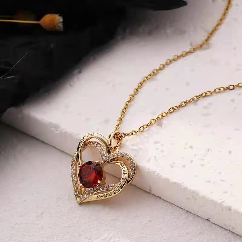 Gold heart red sapphire pendant necklace featuring a central red sapphire gemstone surrounded by diamonds and engraved with the phrase i love you forever.
