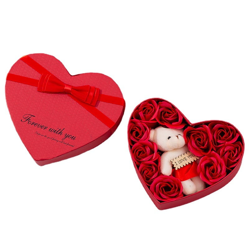Red heart-shaped rose red gift box with a bow containing red roses and a white teddy bear holding an i love you sign for mother’s day.