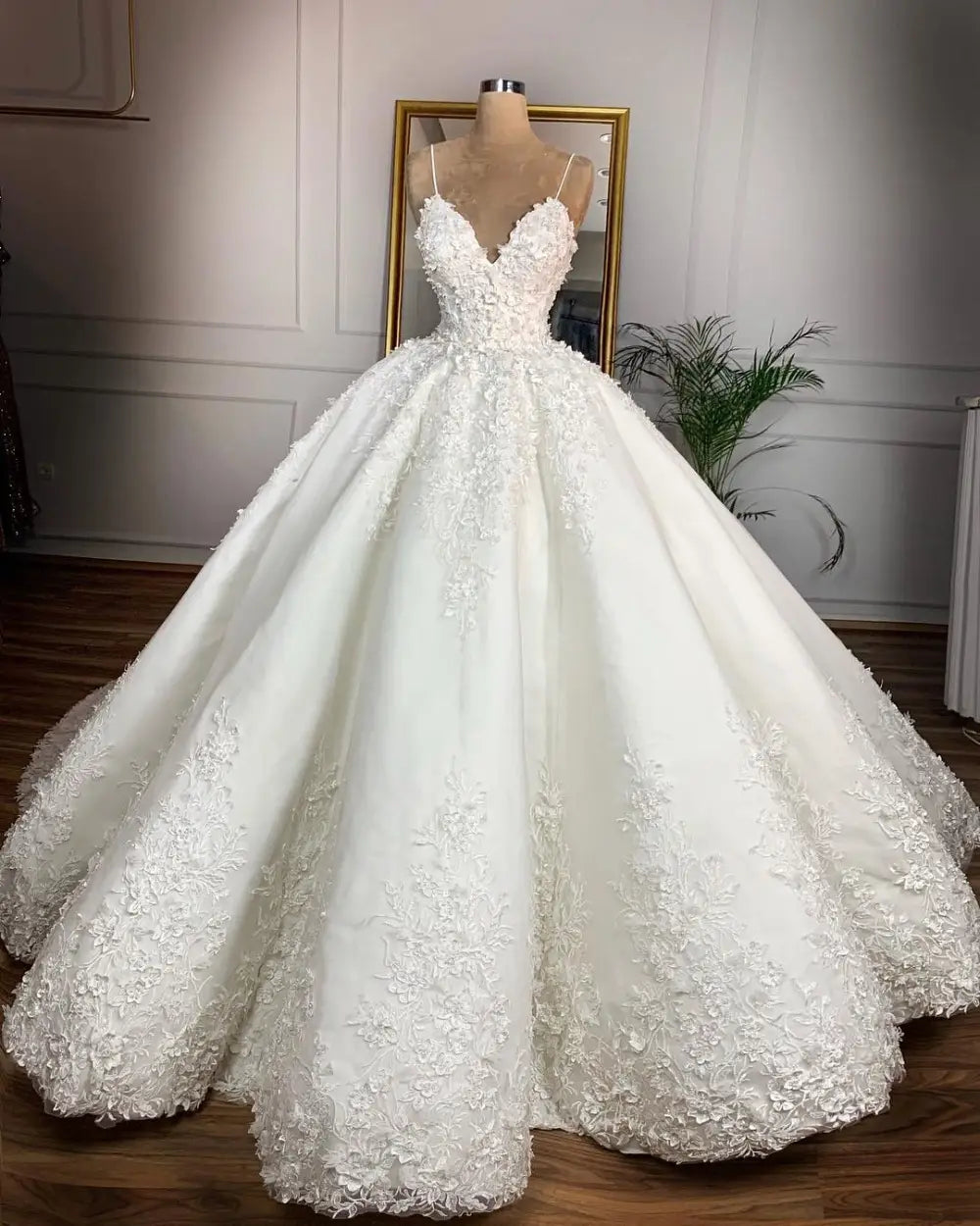 a voluminous white wedding dress with intricate floral lace appliqués and thin spaghetti straps featuring a deep v-neck design ideal for a wedding dress romantic aura look
