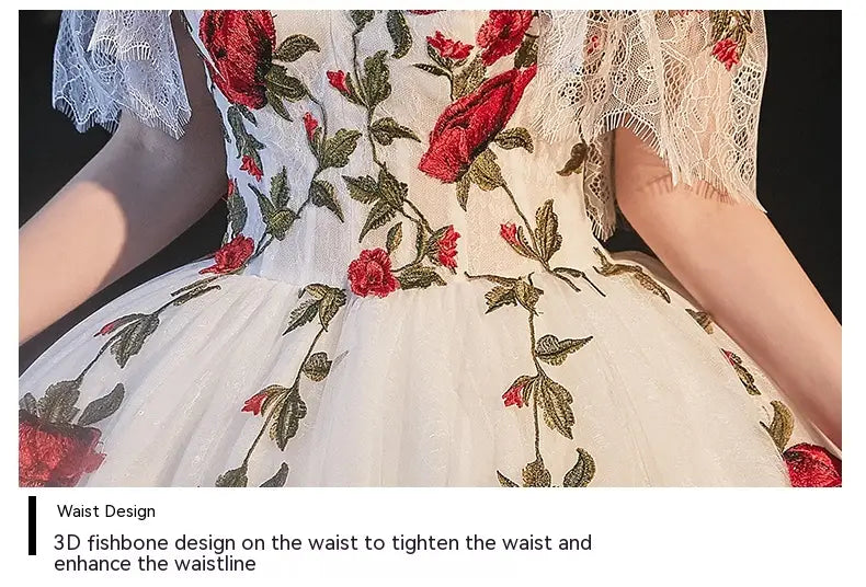 A white lace wedding dress featuring intricate red and green 3d embroidered roses along the bodice and skirt designed for a temperament bride bra style.