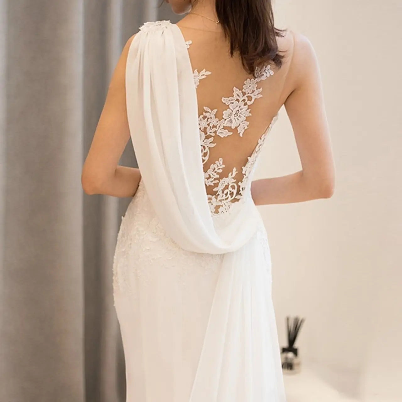white lace mermaid super fairy light wedding dress shown from the back featuring an intricate lace back and draped fabric detail for a light wedding dress style