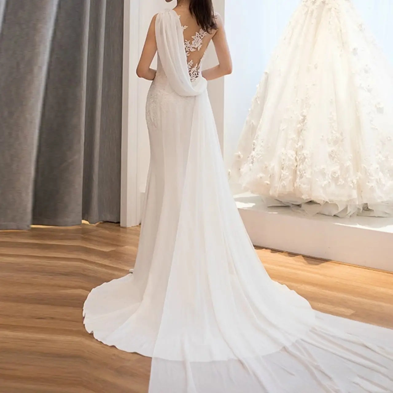 A flowing white lace mermaid super fairy light wedding dress with a delicate lace back and sheer fabric draping elegantly over the shoulders.