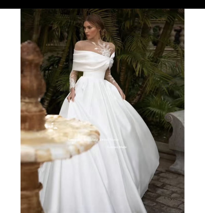 a flowing white long sleeve white raglan sleeve long wedding dress featuring lace detailing on the bodice and sleeves with a full satin-like tutu skirt