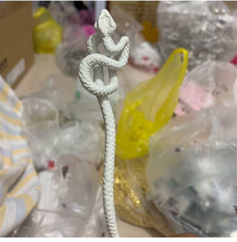 White intricately coiled snake figurine with textured rope-like body and detailed scales decorative on a retro style hairpin.
