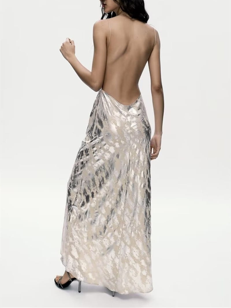 A shimmering silver satin dress with a flowing backless design and delicate spaghetti straps made from metal foil printed fabric for a foil printed underwear dress.