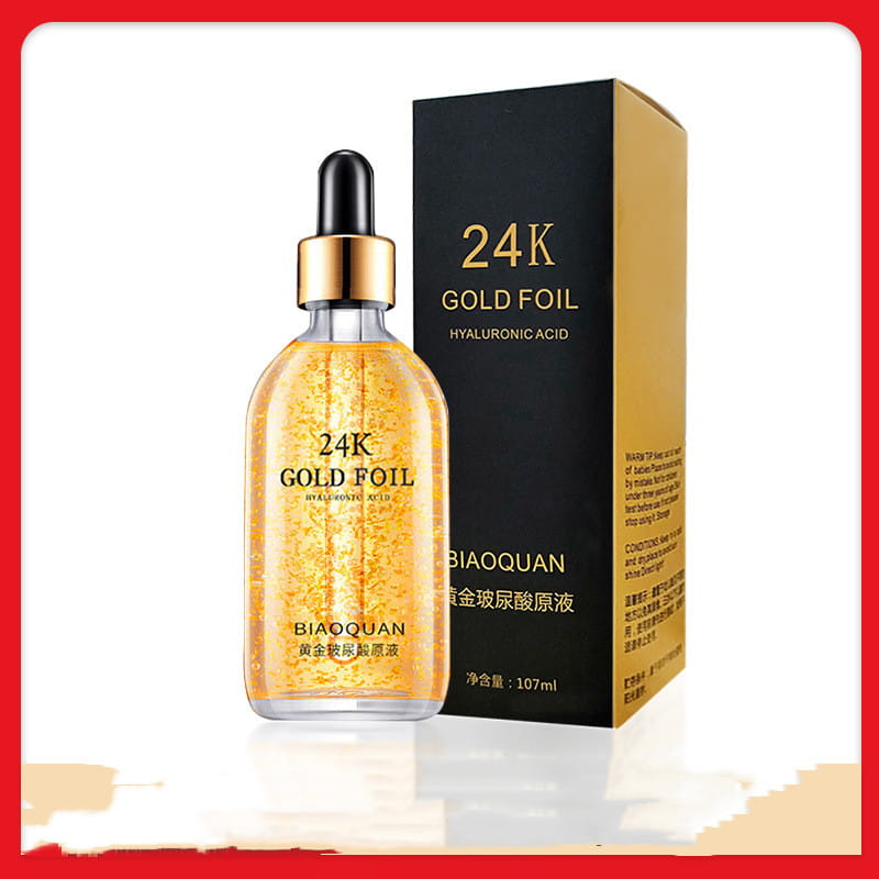 A transparent glass bottle with a gold-colored dropper cap filled with golden-hued 24k gold pure hyaluronic acid essence serum by biaoquan labeled 24k gold foil gold essence serum 100ml.