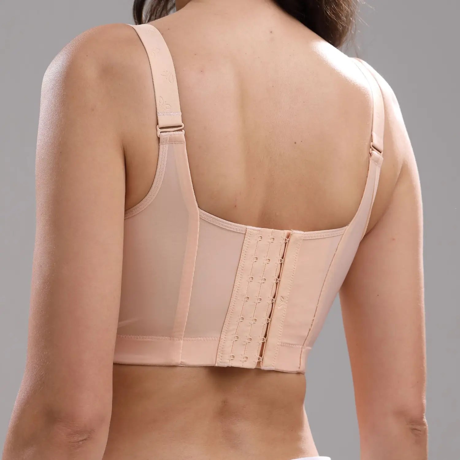 beige underwire plus size bra with adjustable straps and central lace-up back closure shown from the back representing a size bra option.