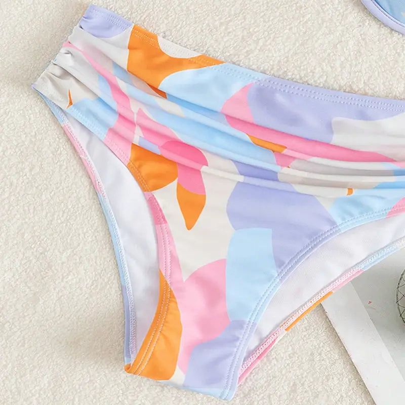 pastel abstract bikini print fashion split swimsuit featuring a pastel-colored bikini bottom with a playful abstract leaf pattern in soft pink orange and lavender hues on stretchy fabric