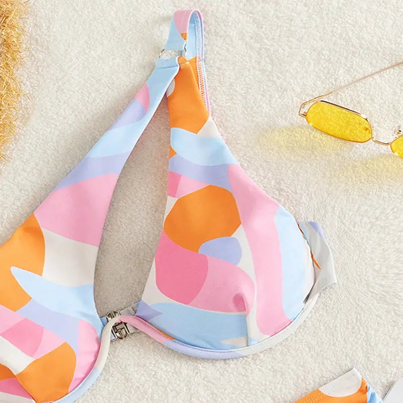 pastel abstract bikini print fashion split swimsuit featuring a pastel-colored bikini top with an abstract geometric pattern in pink orange and light blue on stretchy fabric.