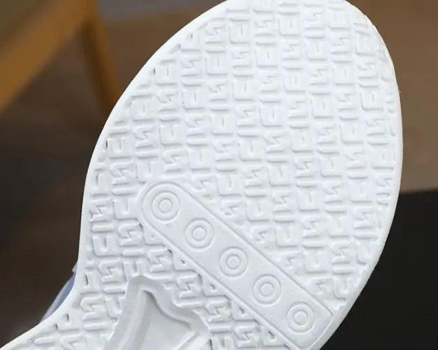 white rubber shoe sole with textured pattern and circular indentations shown on the back side of teal gradient shoes rotating button boy featuring dual network sdx technology and rotating button design
