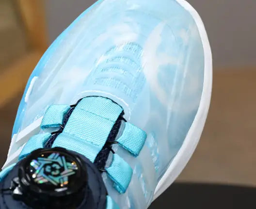 light blue translucent sneaker with teal laces and a black circular dual network sdx rotating button featured in teal gradient shoes rotating button boy collection