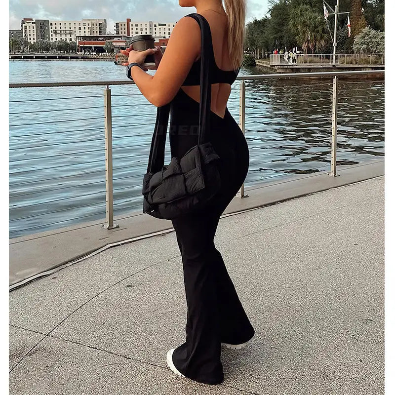black quilted shoulder bag with a sleek modern design and sturdy straps paired with a black flared slim fit hip raise jumpsuit.