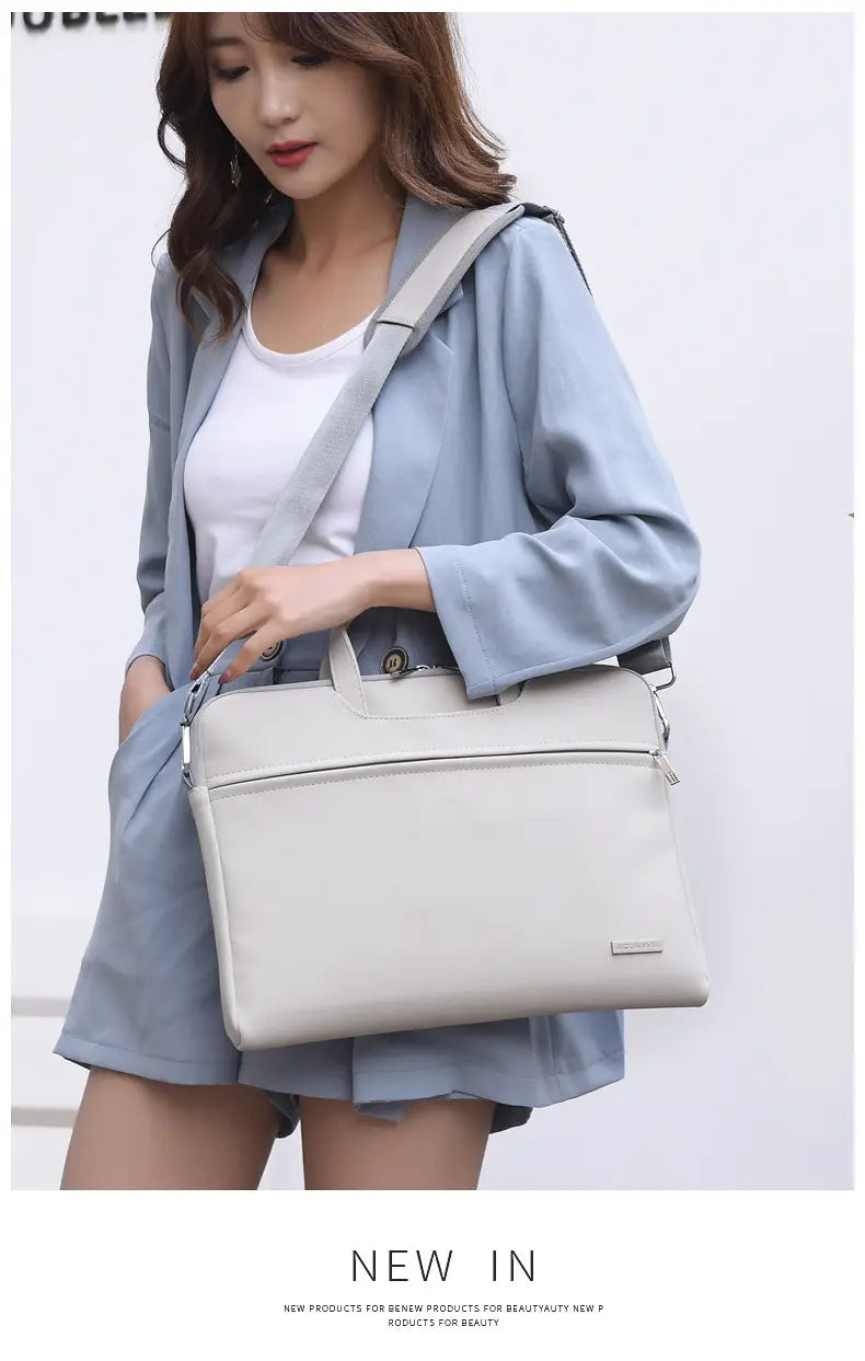 A sleek light gray leather women laptop bag with minimalist design and subtle stitching details for professional use.