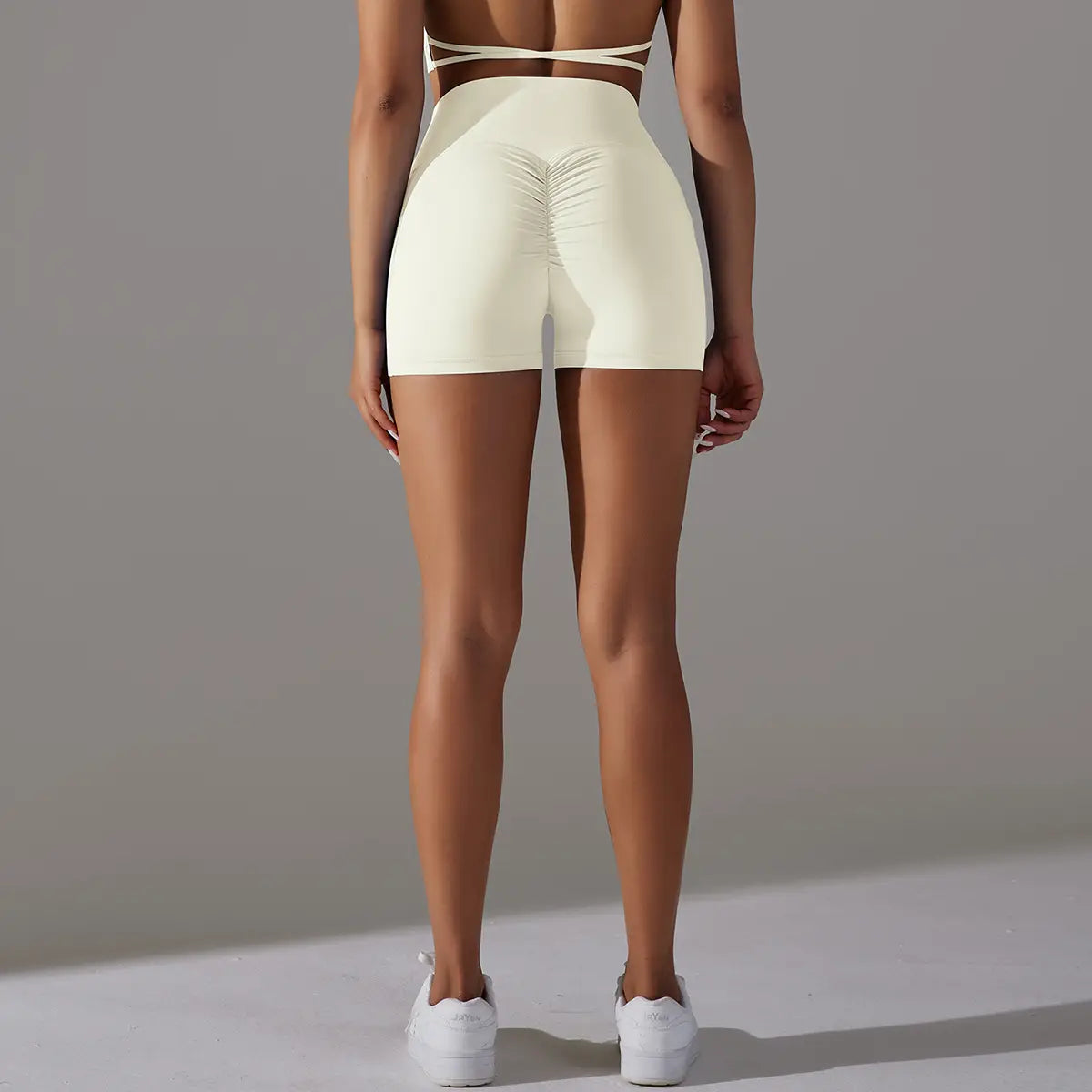 Cream high waisted athletic shorts in cream color with phone pocket design and ruched back design fitness sports style.