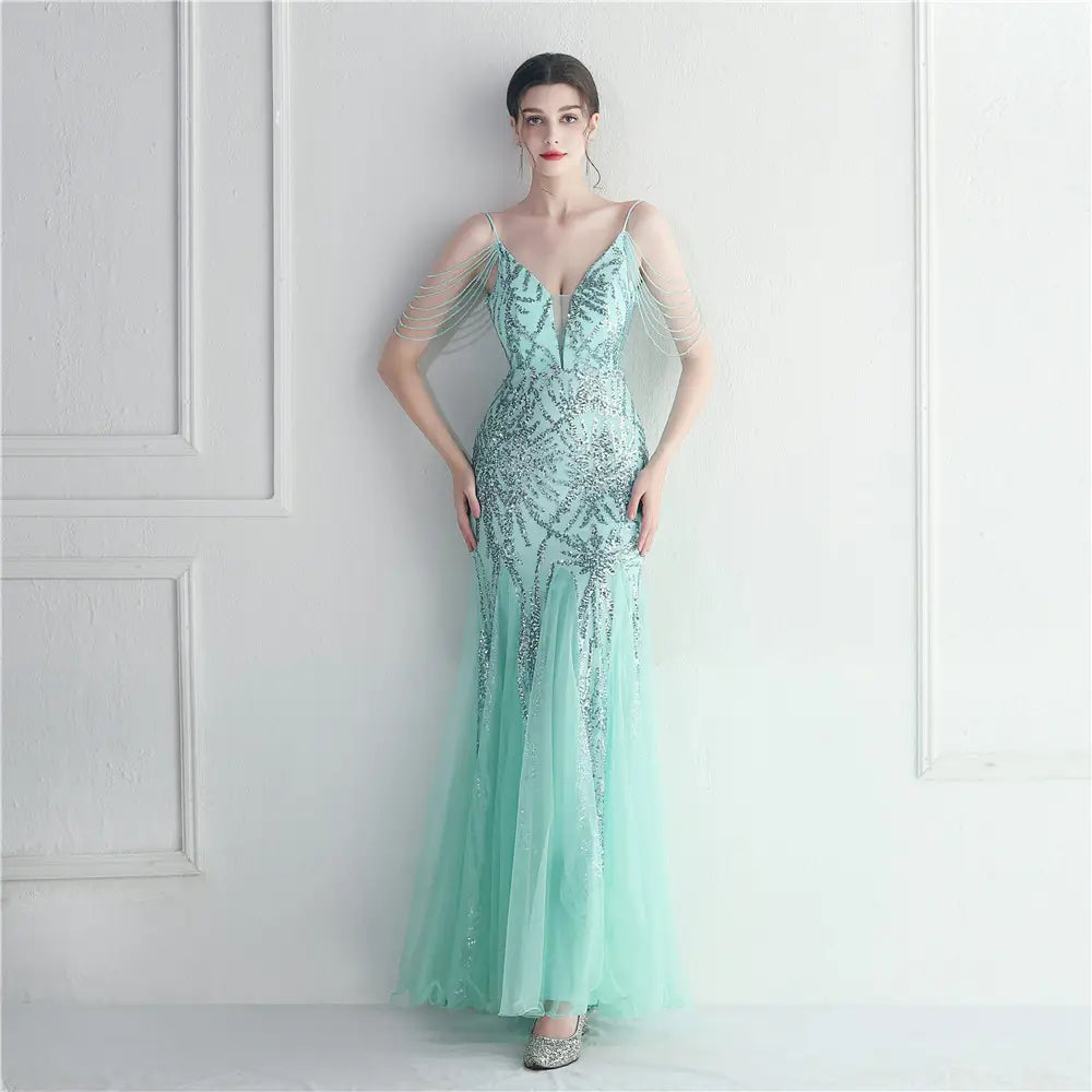 A shimmering mint green mermaid-style gown featuring intricate silver beading and delicate sheer fabric designed as a mesh beaded bridal wedding dinner gown.