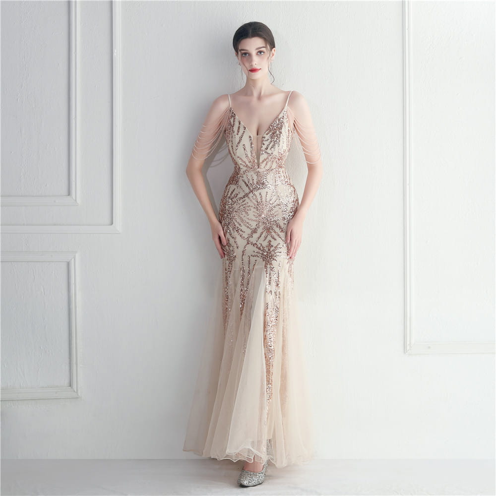 A shimmering champagne-colored evening gown featuring intricate gold sequin patterns and delicate sheer mesh sleeves designed as a mesh beaded bridal wedding dinner gown.