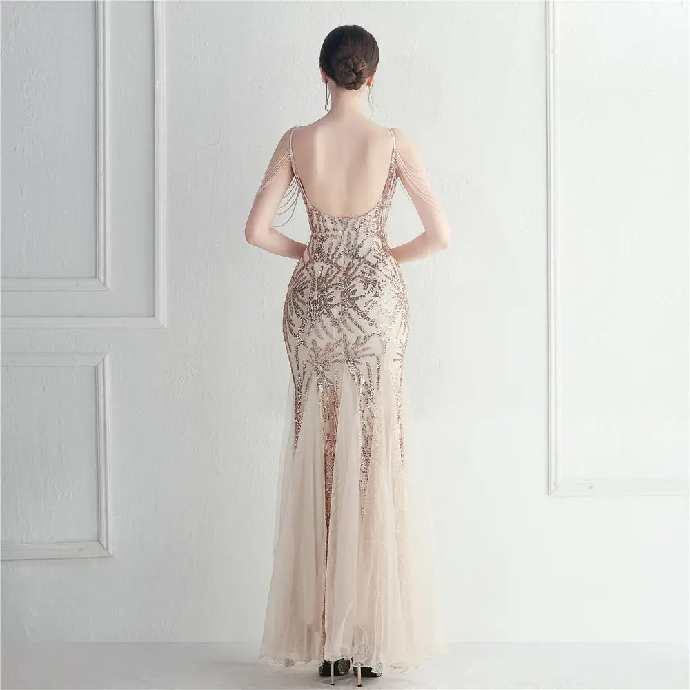 A shimmering champagne-colored mermaid gown featuring intricate sequin patterns and delicate sheer fabric designed as a mesh beaded bridal wedding dinner gown.