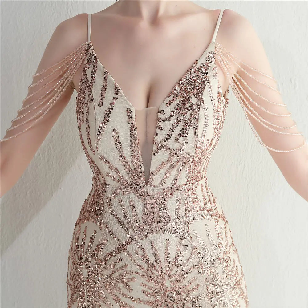 A shimmering rose gold sequined evening gown with delicate spaghetti straps and a plunging v-neckline designed as a mesh beaded bridal wedding dinner gown.