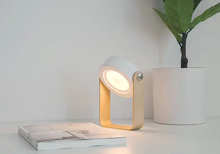 Minimalist white and light wood foldable touch dimmable portable lantern night light with a circular head and adjustable arm for touch dimmable reading.