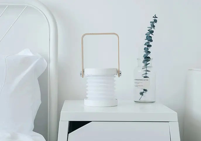 white collapsible foldable touch dimmable portable lantern night light with a light wood handle suitable for touch dimmable reading and ambient lighting.