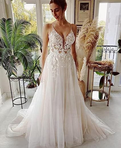 A flowing white wedding dress with intricate wedding dress lace detailing and a deep v-neckline featuring a lace strap design.