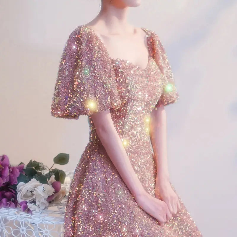 A shimmering rose gold sequined mesh slimming annual party banquet mermaid dress with puffy short sleeves and a square neckline.