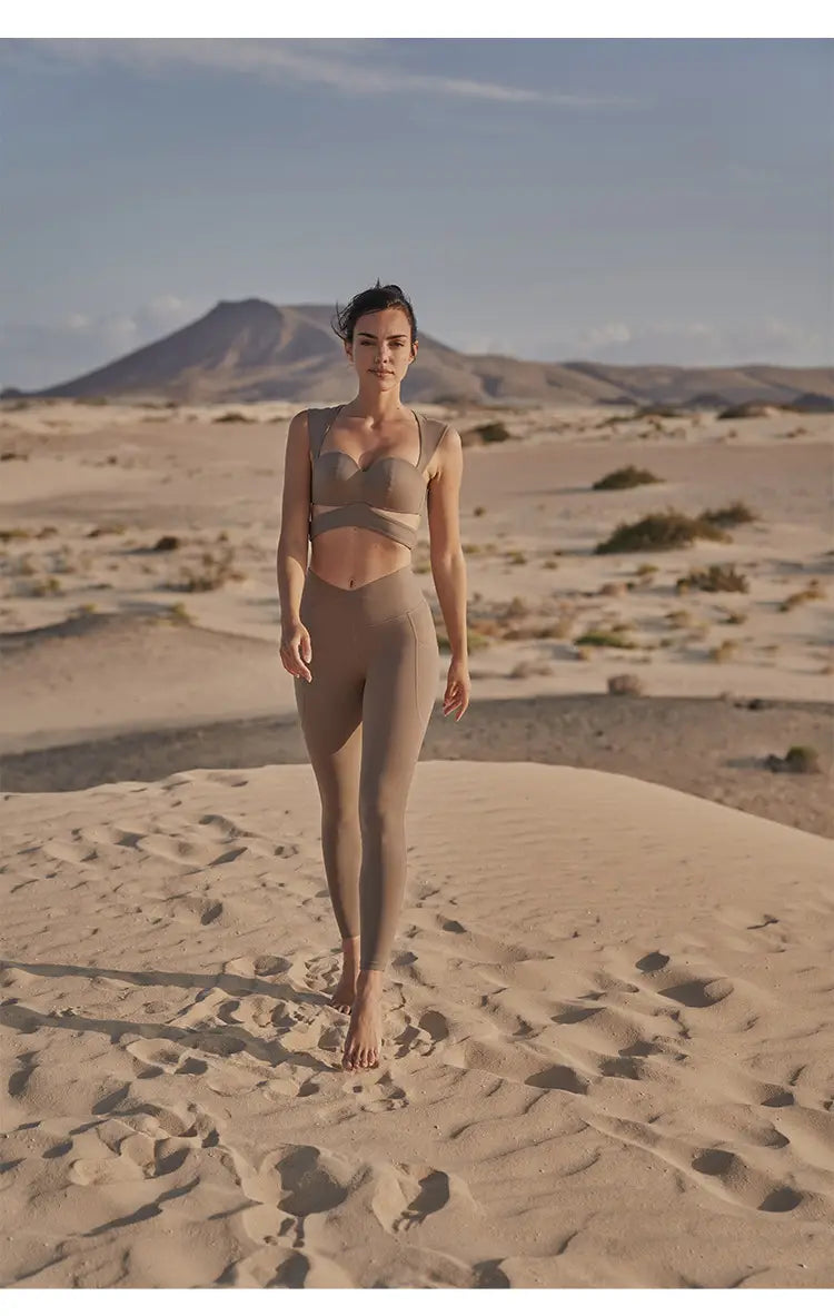 Beige yoga pants and sport coat fitness set in taupe featuring a strappy bra top and high-waisted leggings designed for comfort and movement, paired with a deep black color sport coat.