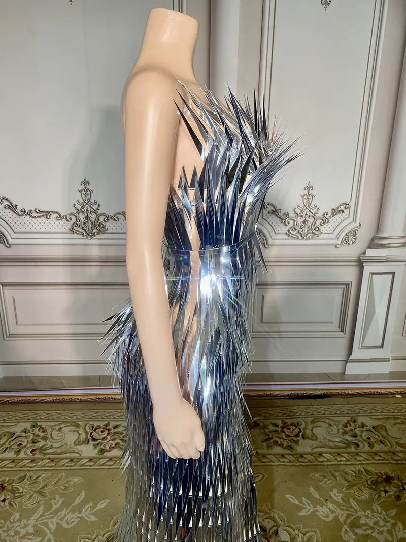A shimmering silver metallic sequined evening dress featuring a dramatic spiky feather-like design cascading from the shoulder to the hem, embodying advanced light luxury for stage performances.