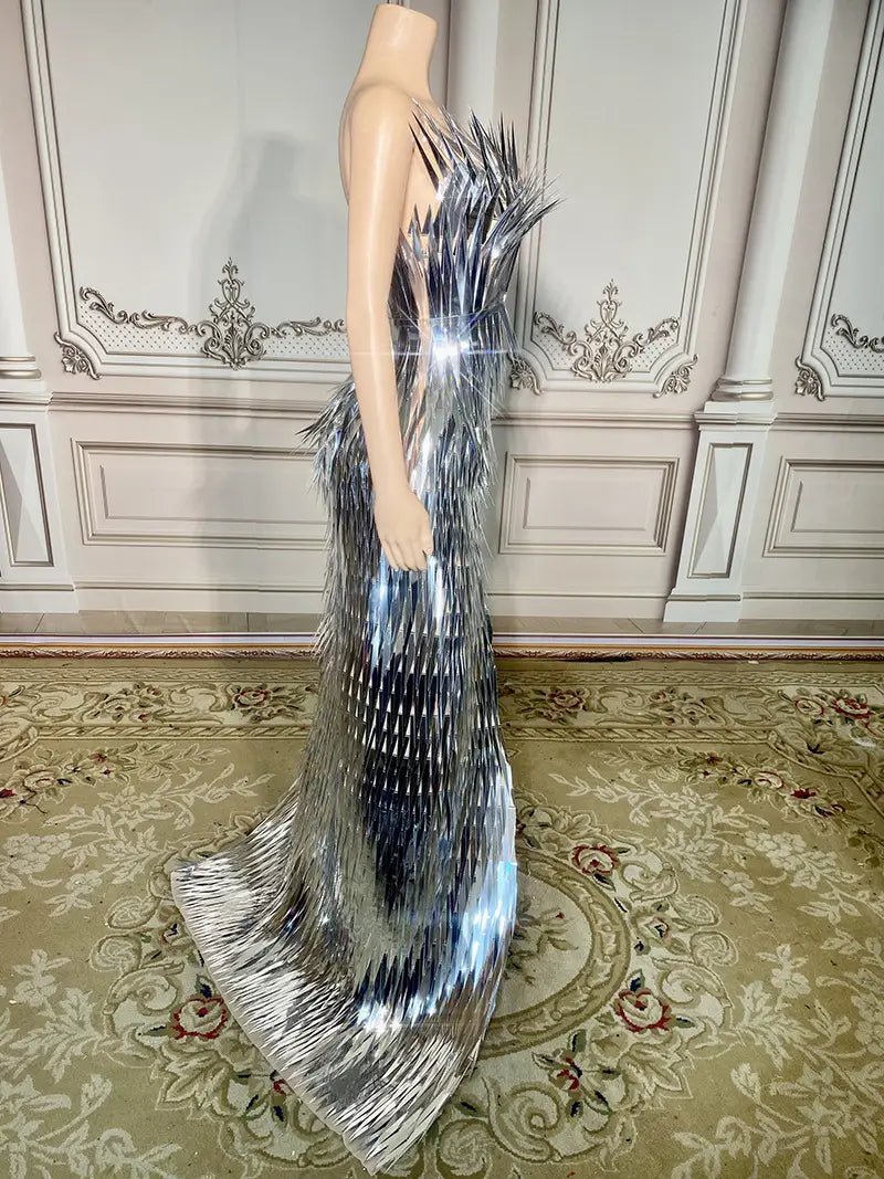 A shimmering silver metallic sequined evening dress with a dramatic spiky back and cascading fringe detailing designed for stage advanced light luxury use.