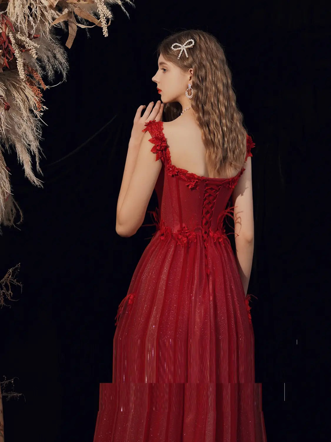 a woman seen from the back wears a deep red wedding toast dress featuring a backless design, lace-up detailing, and a layered tulle skirt with floral appliqués suitable for a toast dress host or dress host annual event.