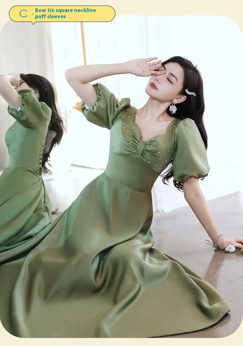 a flowing avocado green sisters group satin midi dress featuring a bow-tie square neckline and puffy sleeves
