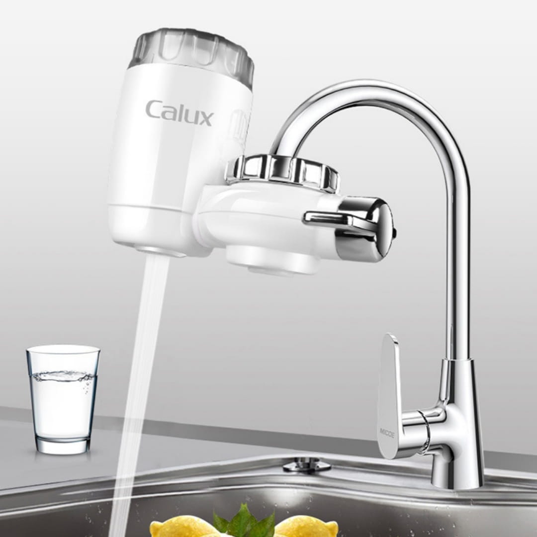 White calux faucet household kitchen front filter with a transparent top cap and chrome accents mounted on a modern kitchen sink.