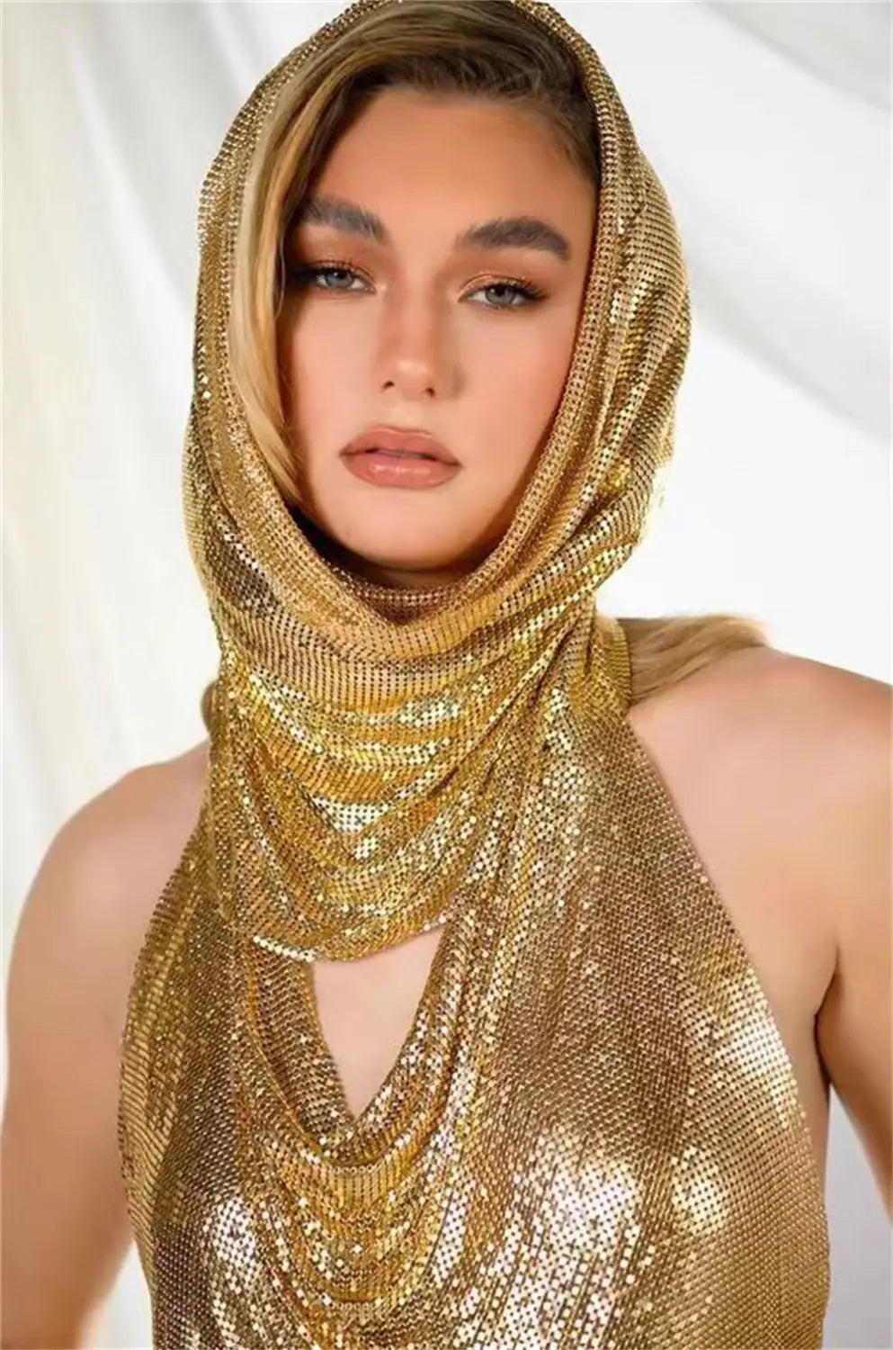 a shimmering gold mesh headscarf with a halter neckline and cascading layers featured in a silver slit metal sequins two-piece set with hood