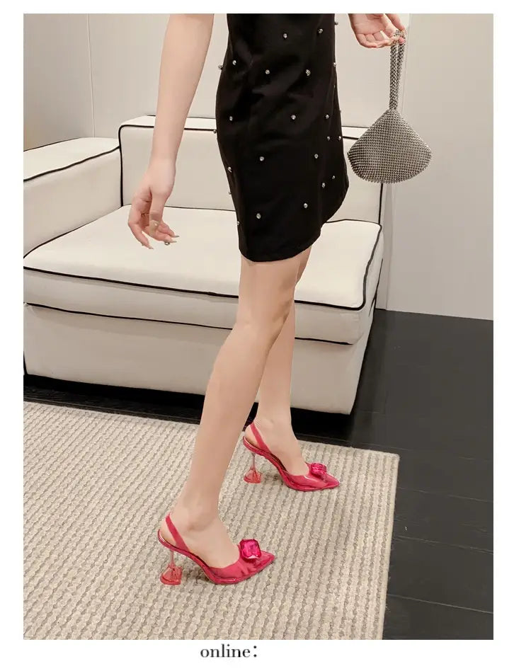 Vibrant pink satin women’s high-heeled sandal featuring a crystal-encrusted bow and transparent glass heel.