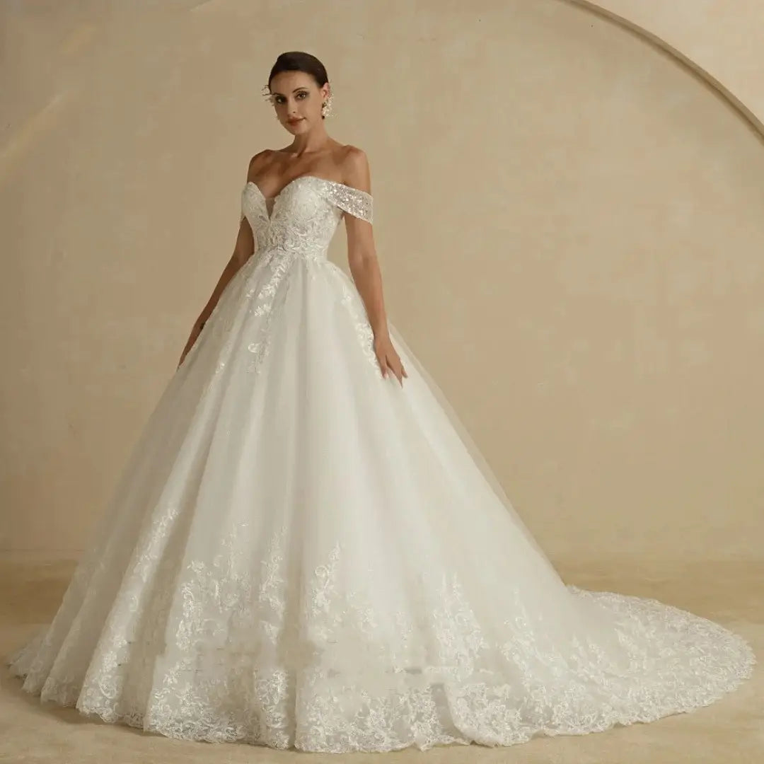 a white off-shoulder wedding dress featuring intricate lace detailing and a flowing ballgown silhouette designed as a bridal main wedding main wedding dress