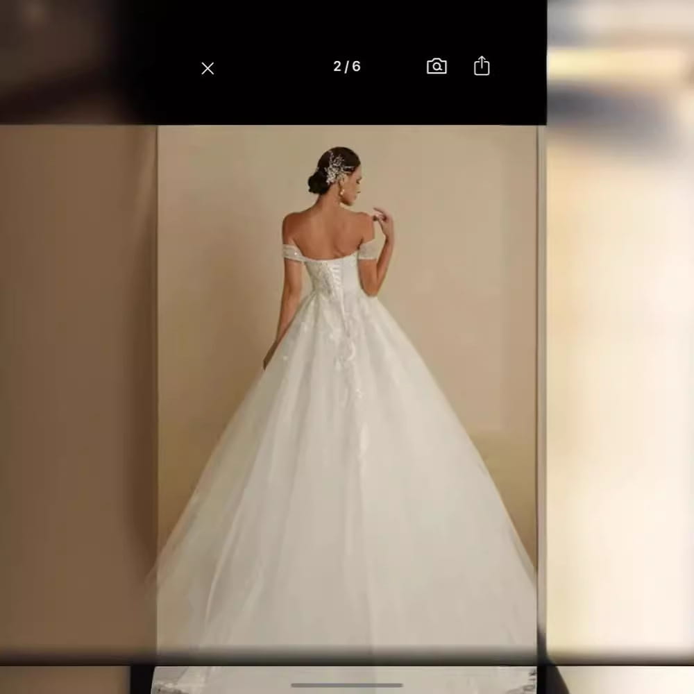 A flowing white off-shoulder lace bridal main wedding dress with voluminous skirt designed as a main wedding dress.
