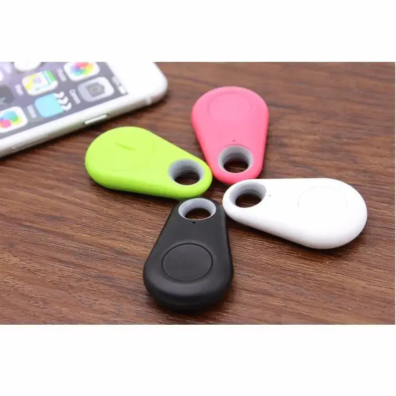 Four colorful silicone bluetooth anti lost object finders in pink lime green black and white shaped like a water drop for easy tracking and prevention of lost objects.