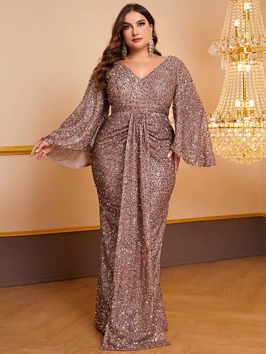 A shimmering rose gold sequin long sleeved gown with a v-neckline and flared bell sleeves.